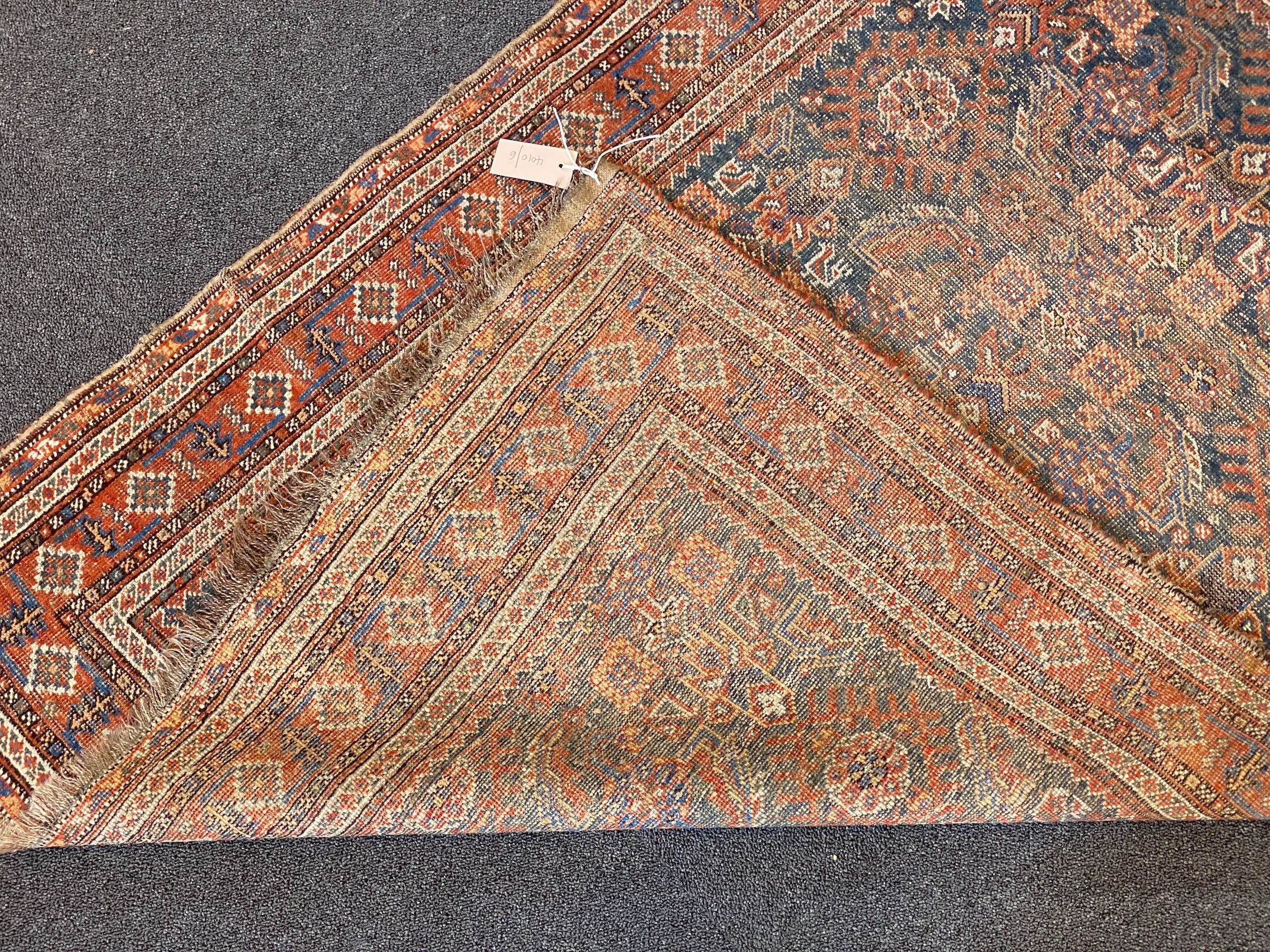 A Shiraz blue ground rug with dense floral field (worn), 144 x 102 cms